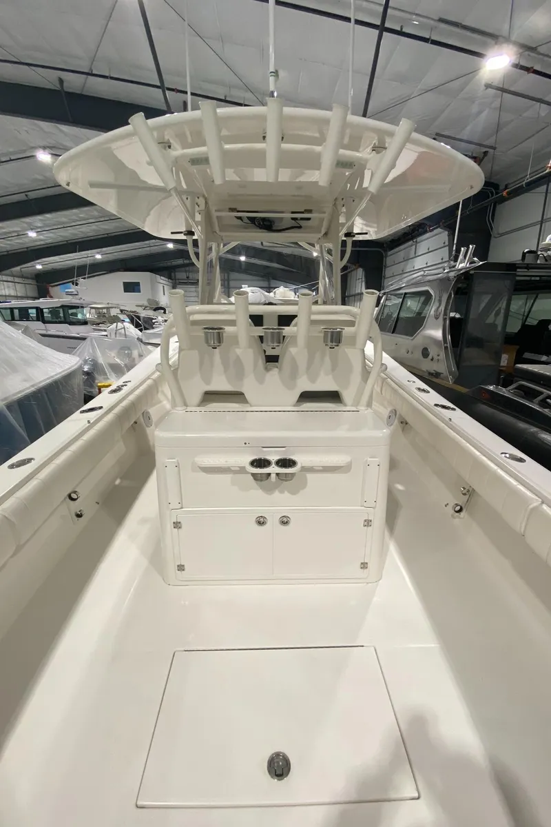 Slide: The Image of 2015 Regulator 34 Center Console boat in a showroom, showcasing spacious deck and seating. - 16
