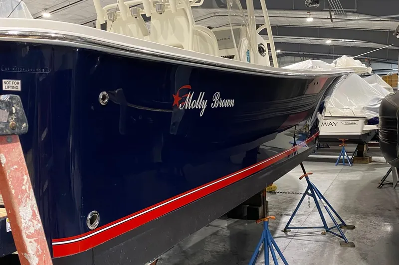 Slide: The Image of 2015 Regulator 34 Center Console boat in storage, blue hull with red accents. - 27