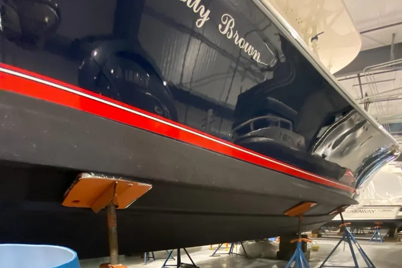 Slide: The Image of 2015 Regulator 34 Center Console boat in storage, featuring a sleek black hull with red stripe. - 40