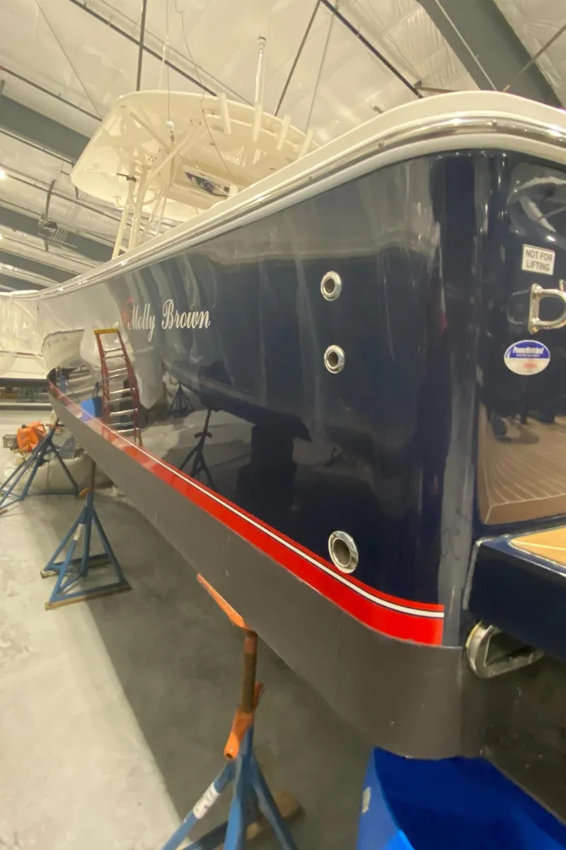 Slide: The Image of 2015 Regulator 34 Center Console boat in storage, blue hull with red stripe. - 42