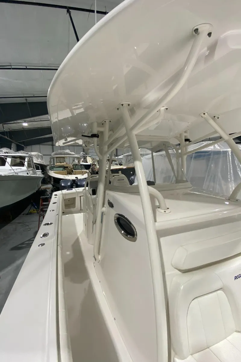 Slide: The Image of 2015 Regulator 34 Center Console boat in a showroom, showcasing sleek design and spacious deck. - 6