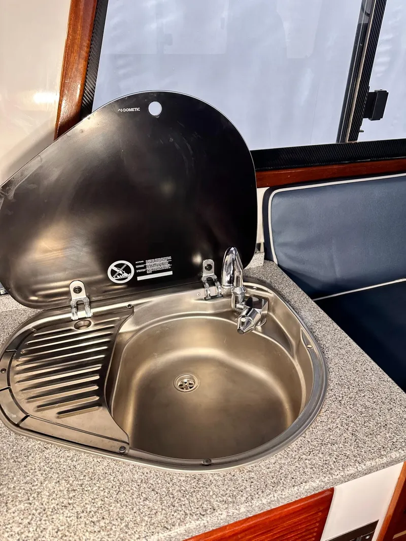 Slide: The Image of 2009 New England Boatworks Hunt 35 interior sink with closed lid and seating area. - 14
