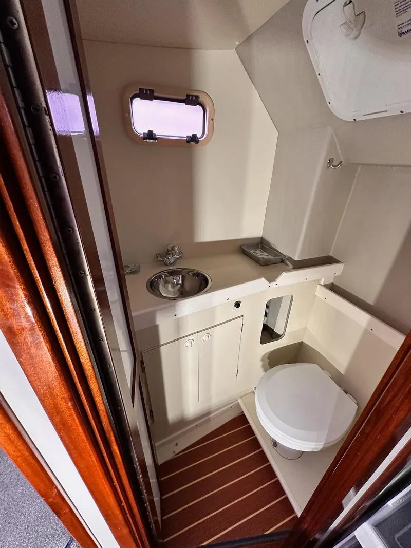 Slide: The Image of 2009 New England Boatworks Hunt 35 bathroom interior with sink, toilet, and porthole window. - 9