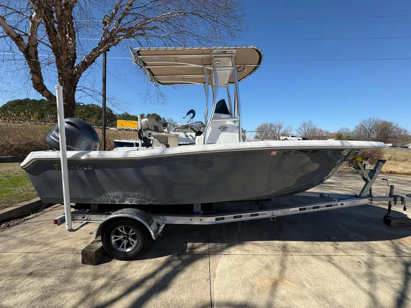 Slide: The Image of 2022 Tidewater 198 CC Adventure boat on trailer, parked outdoors under clear blue sky. - 6