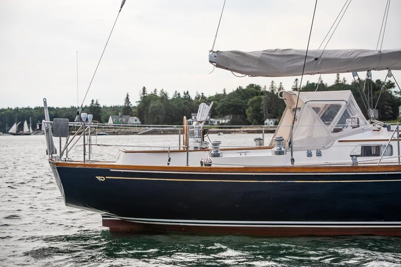 Slide: The Image of Hinckley Sou'wester 42 Sloop, 1994, sailing on calm waters near a forested shoreline. - 11