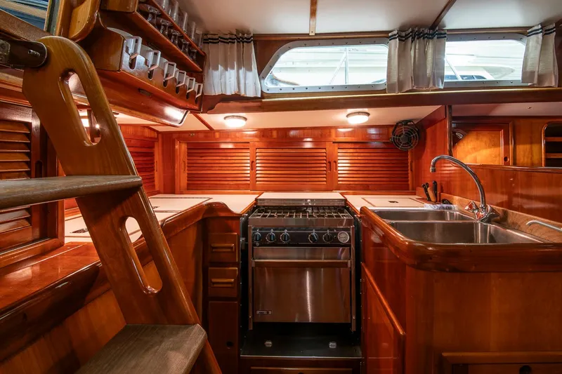 Slide: The Image of Interior of 1994 Hinckley Sou'wester 42 Sloop, featuring wooden cabinetry and a compact kitchen area. - 22