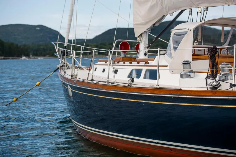 Slide: The Image of Hinckley Sou'wester 42 Sloop, 1994, sailing on calm waters with scenic mountain backdrop. - 12