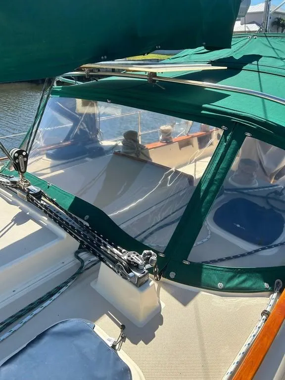 Slide: The Image of 1998 Island Packet 40 sailboat with green canopy and clear windows, docked in sunlight. - 15