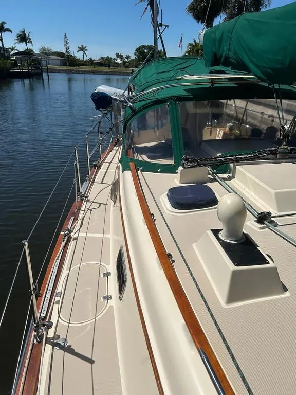Slide: The Image of 1998 Island Packet 40 sailboat docked by a serene waterfront with green canopy. - 16