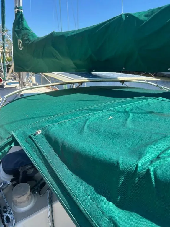 Slide: The Image of 1998 Island Packet 40 sailboat with green canvas covers and clear blue sky. - 21