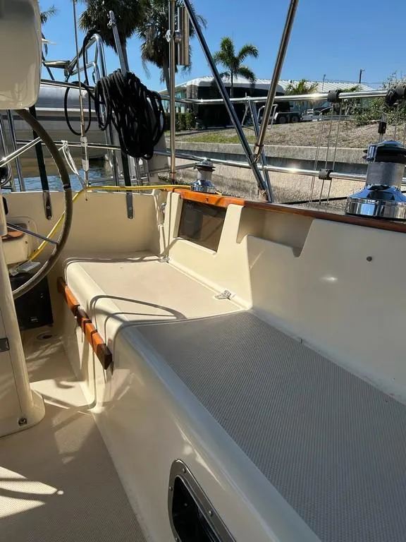 Slide: The Image of 1998 Island Packet 40 sailboat cockpit with seating and steering wheel, under sunny skies. - 29