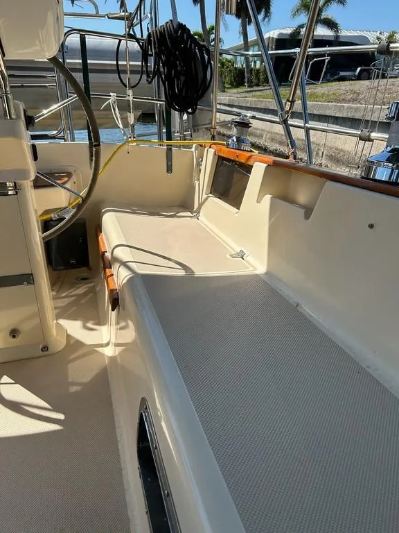 Slide: The Image of 1998 Island Packet 40 sailboat cockpit with seating and steering wheel, docked under sunny skies. - 39