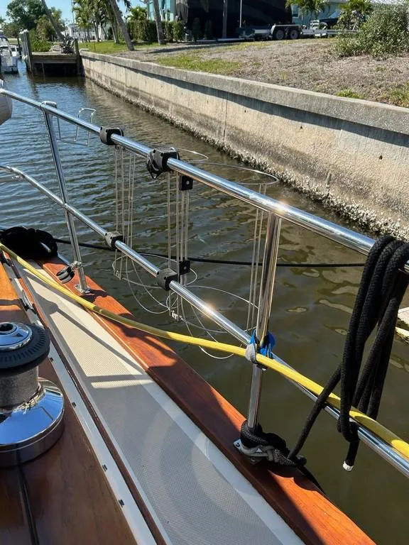 Slide: The Image of 1998 Island Packet 40 sailboat deck with railing and ropes, docked in a canal. - 43