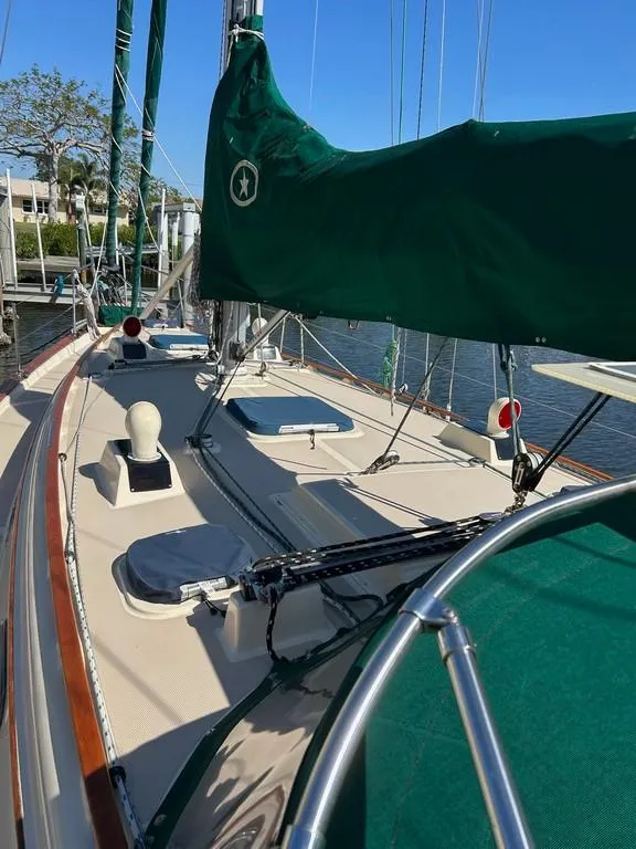 Slide: The Image of 1998 Island Packet 40 sailboat deck with green sail cover, docked by the water. - 45