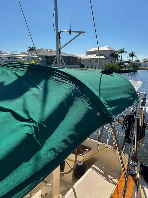 Slide: The Image of 1998 Island Packet 40 sailboat with green canopy, docked in a sunny marina. - 46