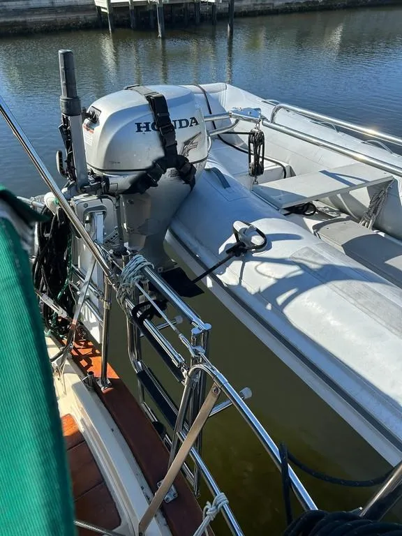 Slide: The Image of 1998 Island Packet 40 sailboat with Honda outboard motor docked by the water. - 7