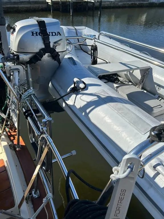 Slide: The Image of 1998 Island Packet 40 sailboat with Honda outboard motor docked by the water. - 9