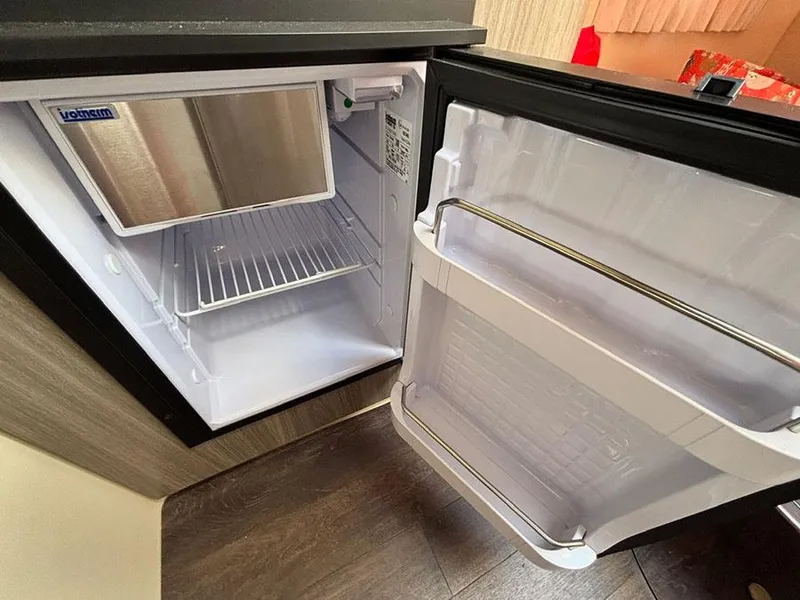 Slide: The Image of Open mini fridge inside 2020 Regal 28 Express boat, showing empty shelves and door storage. - 10