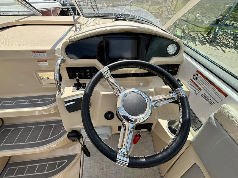 Slide: The Image of 2020 Regal 28 Express boat helm with steering wheel and control panel. - 2