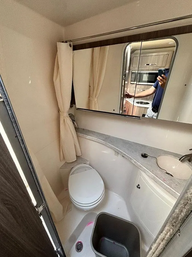 Slide: The Image of 2020 Regal 28 Express bathroom with toilet, sink, and mirror in compact design. - 8