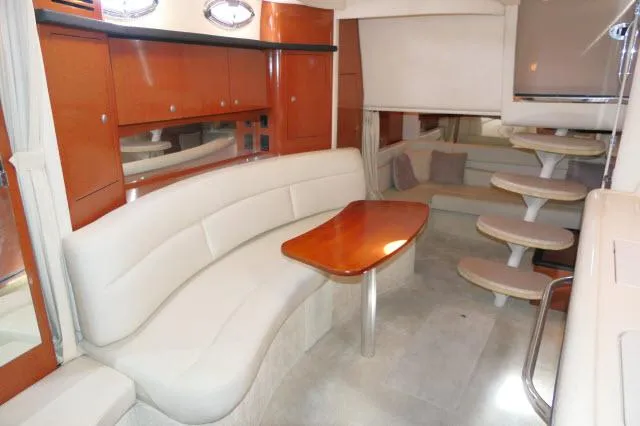 Slide: The Image of Interior of 2005 Sea Ray 340 Sundancer with white seating and wooden table. - 12