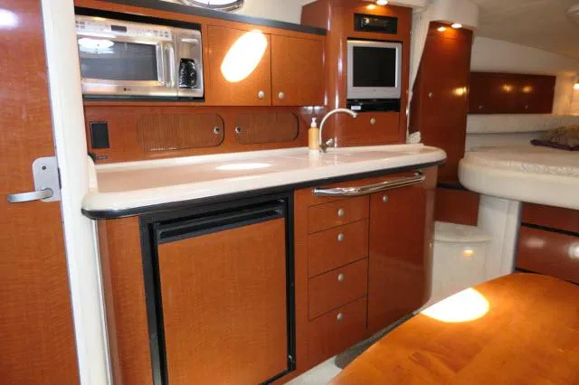 Slide: The Image of 2005 Sea Ray 340 Sundancer interior kitchen with wood cabinetry, microwave, and compact fridge. - 4