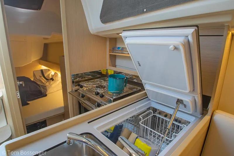 Slide: The Image of Interior of 2022 Beneteau Oceanis 30.1 yacht kitchen with stove, sink, and open fridge. - 11