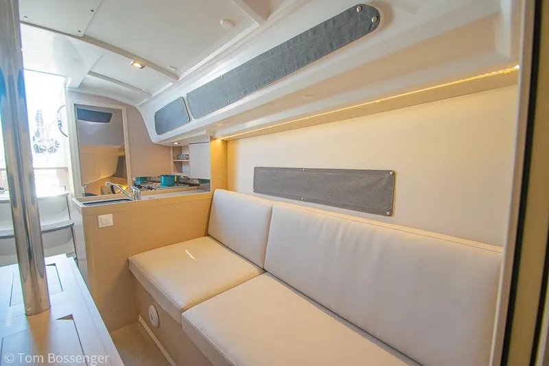 Slide: The Image of Interior of 2022 Beneteau Oceanis 30.1 yacht, featuring a cozy seating area and kitchenette. - 17