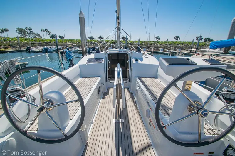 Slide: The Image of 2022 Beneteau Oceanis 30.1 sailboat cockpit with dual steering wheels, docked in a marina. - 4