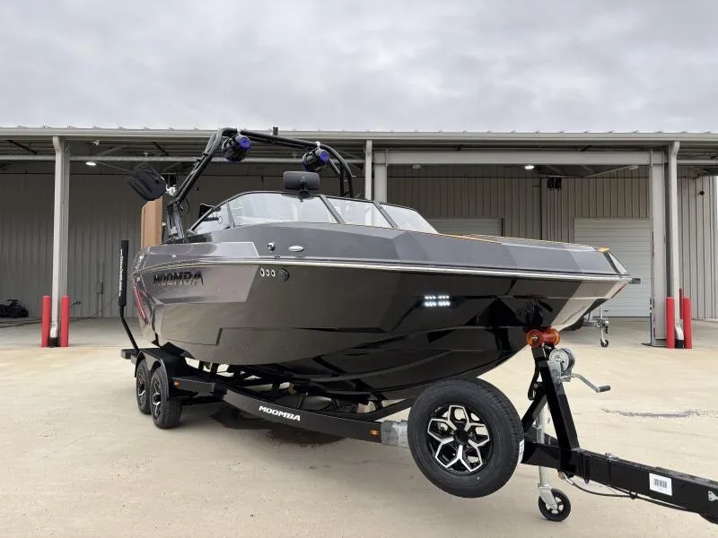 Slide: The Image of 2025 Moomba Max boat on trailer, parked outside industrial building. - 1