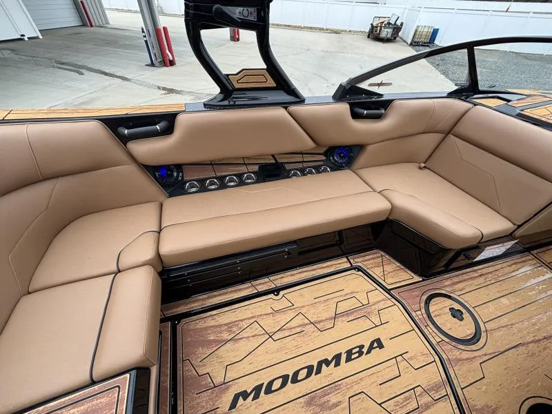 Slide: The Image of 2025 Moomba Max boat interior with tan seating and wood-style flooring. - 12