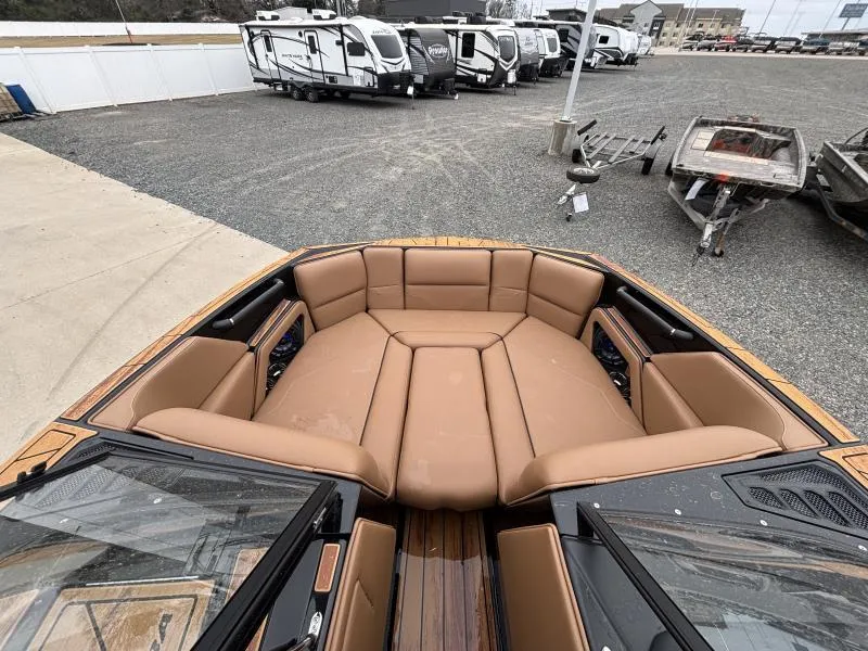 Slide: The Image of 2025 Moomba Max boat interior with tan seating, parked near RVs and trailers. - 16