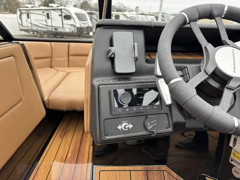 Slide: The Image of 2025 Moomba Max boat interior with steering wheel and control panel, featuring tan seating. - 18