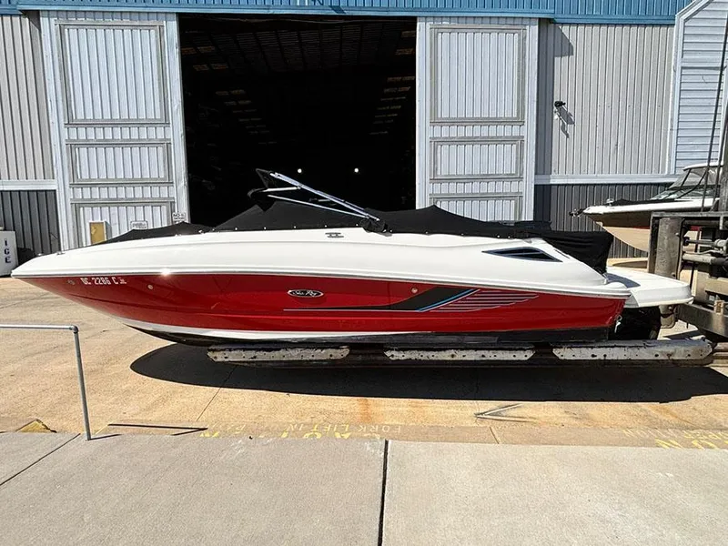 Slide: The Image of 2016 Sea Ray 240 Sundeck boat with red hull, docked outside a warehouse. - 3