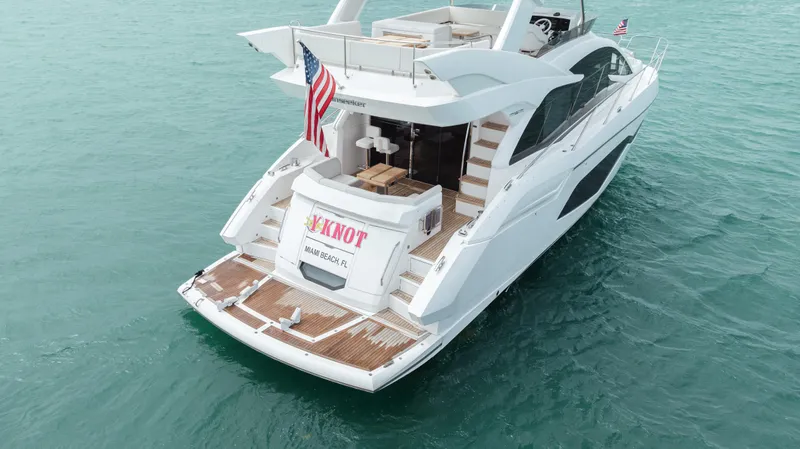 Slide: The Image of 2020 Sunseeker 52 Manhattan yacht on turquoise water, rear view with American flag. - 6