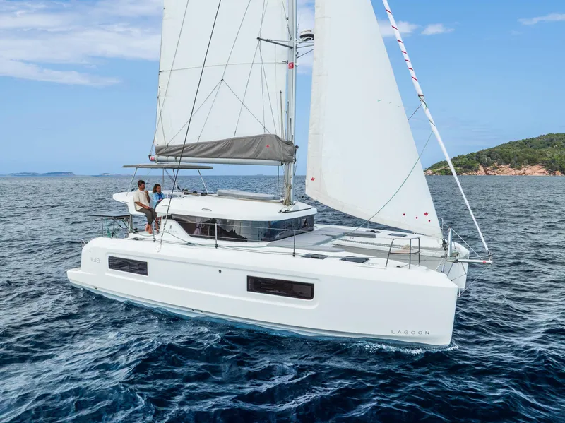 Slide: The Image of 2025 Lagoon 38 catamaran sailing on open sea with two people onboard. - 64