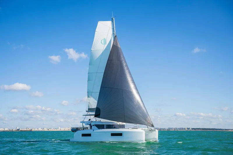 Slide: The Image of 2025 Lagoon 38 catamaran sailing on open water under clear blue skies. - 80