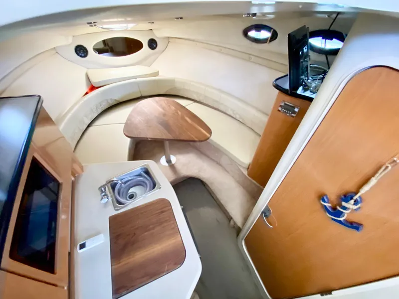 Slide: The Image of 2001 Regal 2660 Commodore cabin interior with kitchenette, seating, and wood accents. - 11