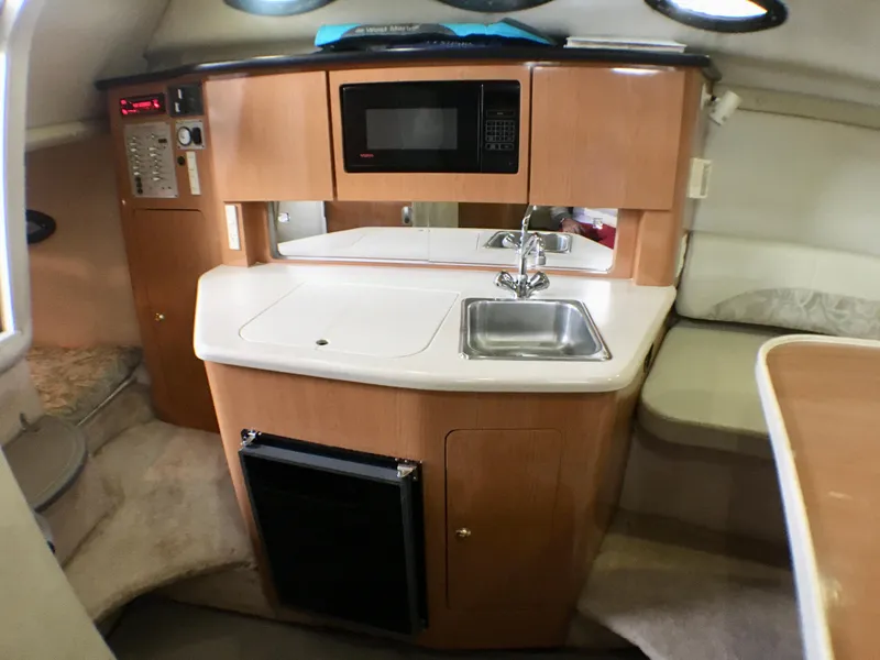 Slide: The Image of 2001 Regal 2660 COMMODORE boat interior with kitchenette, microwave, sink, and compact fridge. - 14