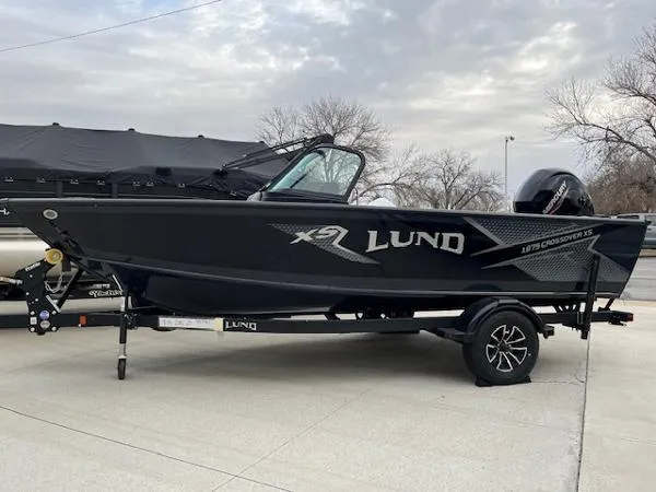 Slide: The Image of 2025 Lund 1875 Crossover XS boat on trailer, parked outdoors. - 0