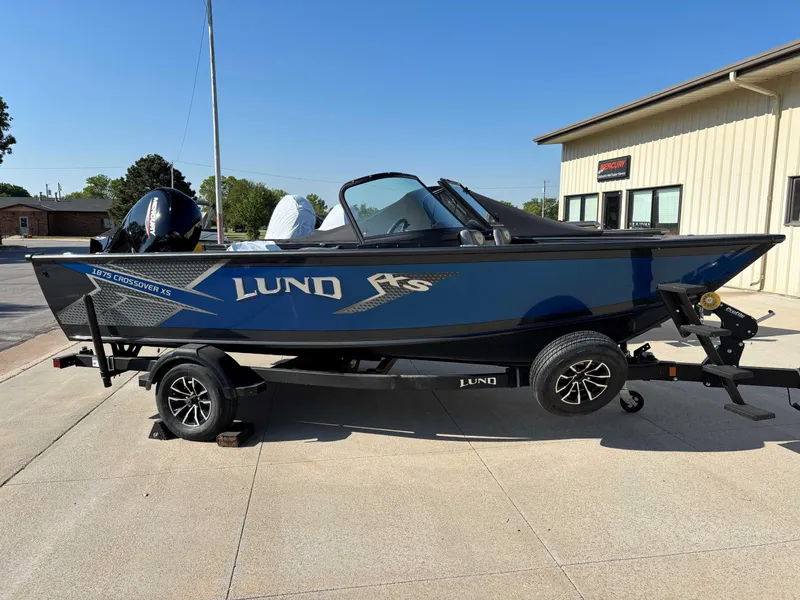 Slide: The Image of 2025 Lund 1875 Crossover XS boat on trailer, parked outdoors, side view. - 1
