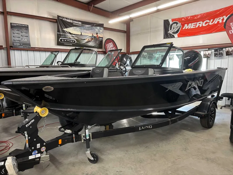 Slide: The Image of 2025 Lund 1875 Crossover XS boat in showroom, black exterior, on trailer. - 2