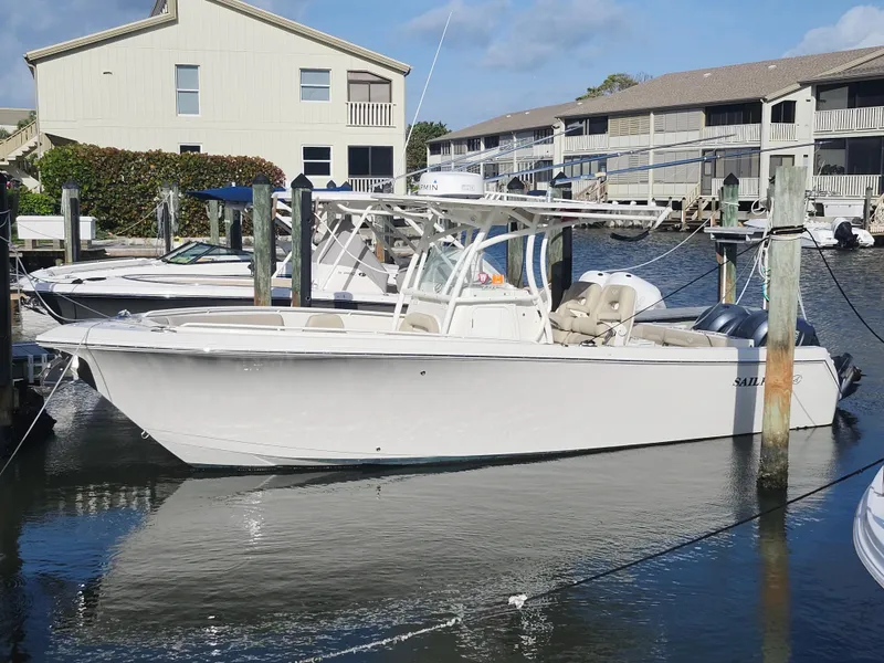 Slide: The Image of 2018 Sailfish 270 CC boat docked in a marina, surrounded by residential buildings. - 2