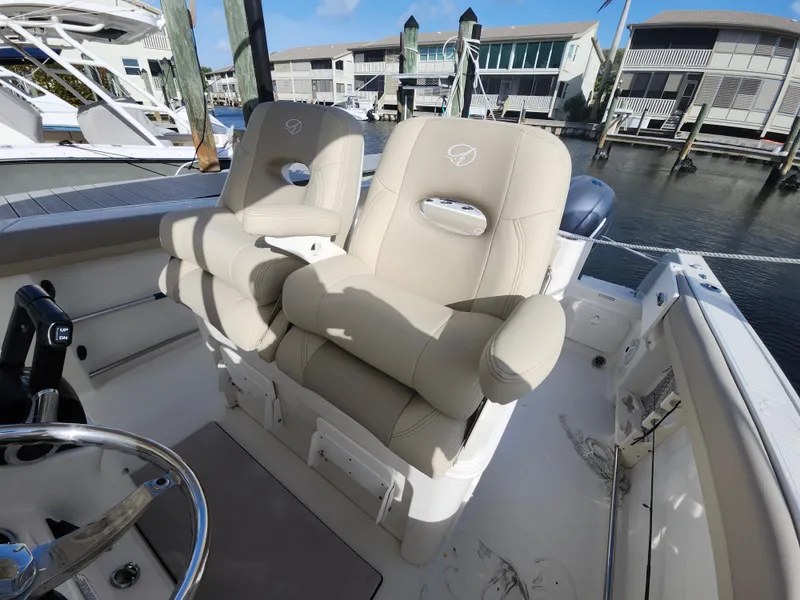Slide: The Image of 2018 Sailfish 270 CC boat with beige captain seats, docked at a marina. - 8