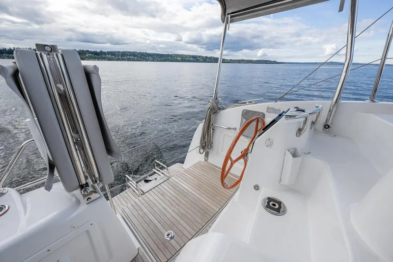 Slide: The Image of 2025 Excess 11 yacht cockpit with wooden deck and orange steering wheel on calm water. - 16
