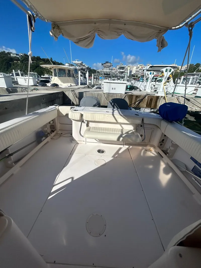 Slide: The Image of 2005 Grady-White Marlin 300 boat interior at marina, featuring spacious seating and canopy. - 10