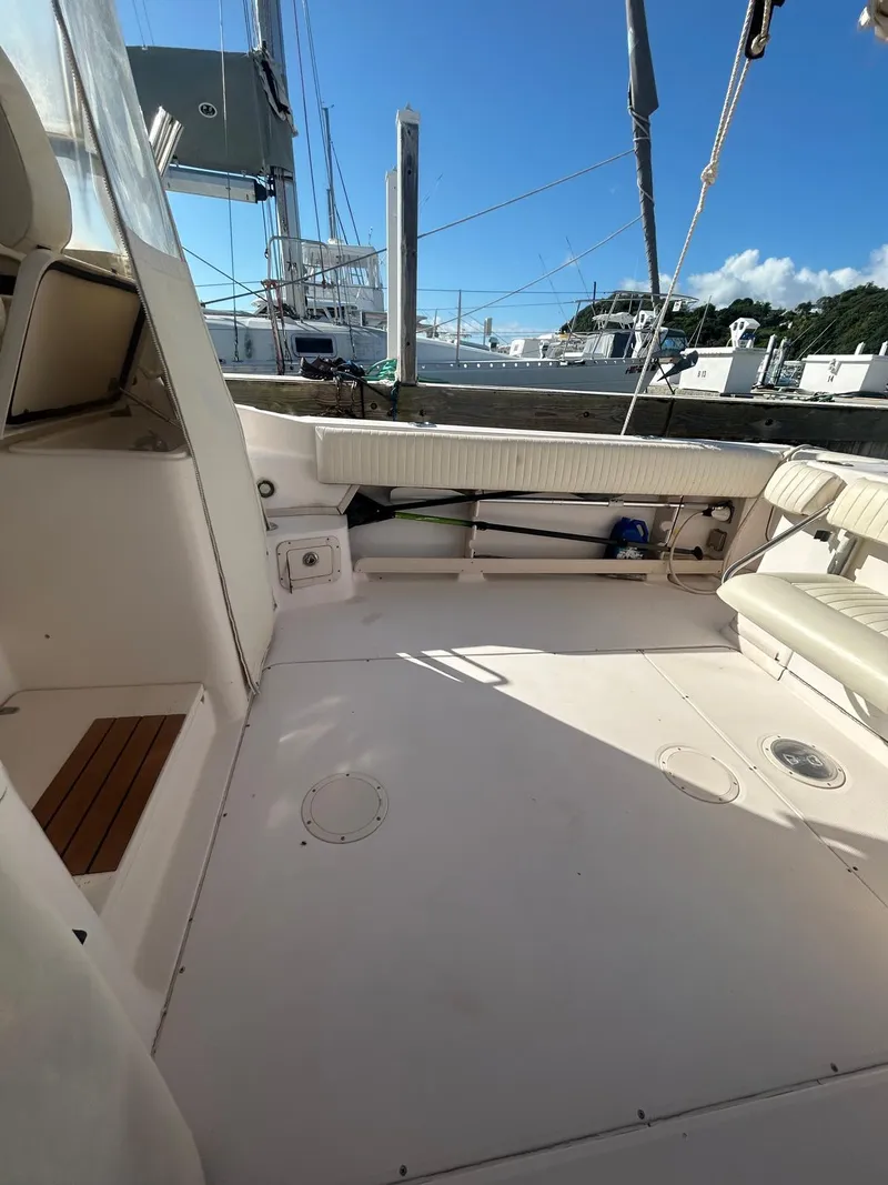 Slide: The Image of 2005 Grady-White Marlin 300 boat deck with seating, docked under clear blue sky. - 6