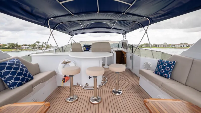 Slide: The Image of 1998 Hatteras 74 Sport Deck Motor Yacht with spacious seating and bar stools under a canopy. - 25