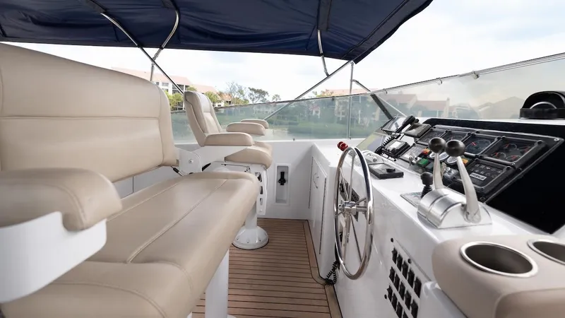 Slide: The Image of 1998 Hatteras 74 Sport Deck Motor Yacht helm with beige seating and navigation controls. - 29