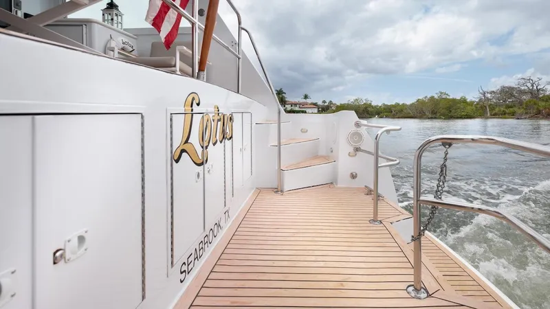 Slide: The Image of 1998 Hatteras 74 Sport Deck Motor Yacht, teak deck, American flag, serene waterway backdrop. - 31